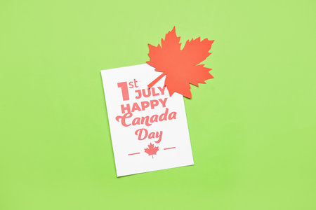 Maple leaf and paper card with text 1ST JULY HAPPY CANADA DAY on green backgroundの写真素材