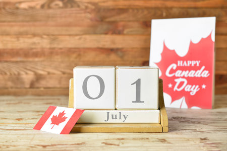 Cube calendar with date July 1 and Canadian flag on wooden table. Happy Canada Day