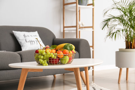 Table with fruit basket near sofa in living roomの写真素材