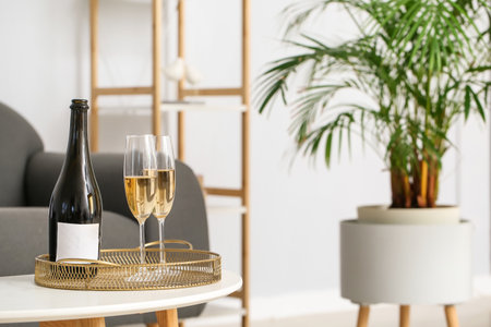 Tray with bottle of champagne and glasses on table in living roomの写真素材