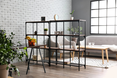 Interior of modern room with sofa, shelf unit and fruit basket on table near gray brick wall