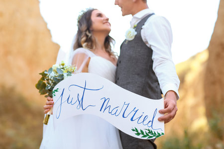 Happy wedding couple with poster in countrysideの写真素材