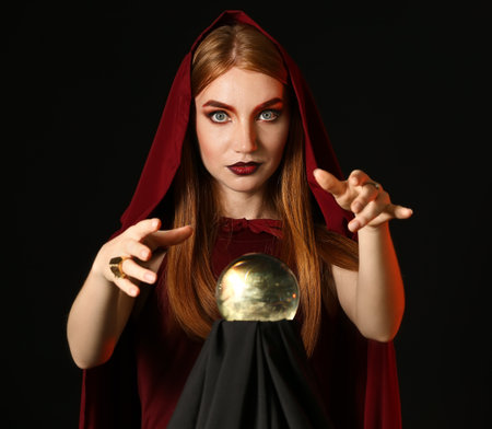 Young witch with crystal ball on dark backgroundの写真素材