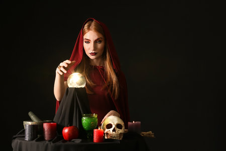 Witch performing ritual on dark background