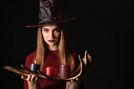 Young witch with candles on dark backgroundの写真素材