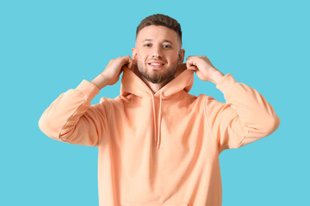 Young guy in stylish hoodie on color backgroundの写真素材
