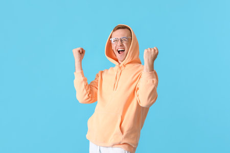 Happy young guy in stylish hoodie on color backgroundの写真素材