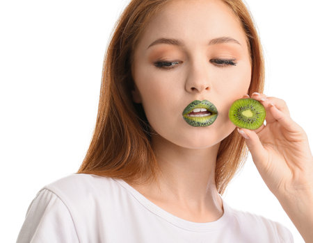 Beautiful young woman with unusual makeup and kiwi on white backgroundの写真素材
