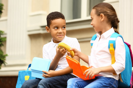 Cute little pupils having lunch outdoors