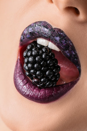 Beautiful young woman with unusual makeup and blackberry, closeupの写真素材