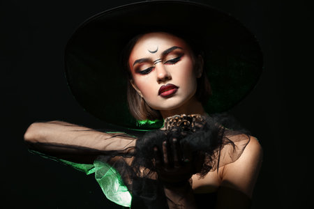 Young witch with spider on dark background
