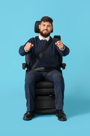 Handsome man with imaginary steering wheel in car seat on blue backgroundの写真素材