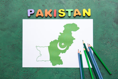 Paper sheet with flag map of Pakistan and pencils on color backgroundの写真素材