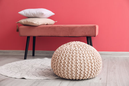 Comfortable pouf on wooden floor near bench with pillows in roomの写真素材