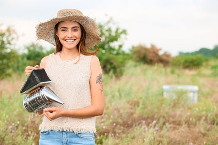 Female beekeeper with smoker at apiaryの写真素材