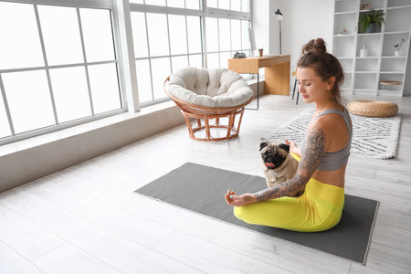 Young woman with cute pug dog meditating at homeの写真素材