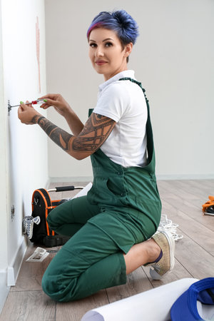 Female electrician repairing socket in room