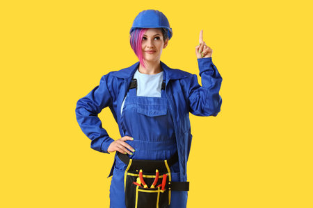 Female electrician pointing at something on color backgroundの写真素材