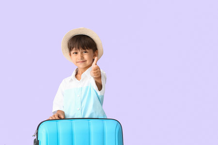 Little boy with suitcase showing thumb-up on color backgroundの写真素材