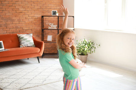 Little redhead girl in green t-shirt dancing at homeの写真素材