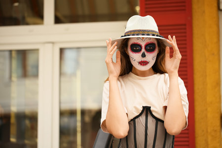 Young woman with painted skull on her face outdoors. Celebration of Mexico's Day of the Dead (El Dia de Muertos)の写真素材