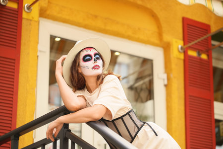 Young woman with painted skull on her face outdoors. Celebration of Mexico's Day of the Dead (El Dia...