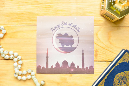Greeting card for Eid al-Adha (Feast of the Sacrifice) with Quran, lamp and tasbih on wooden...
