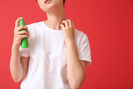 Young woman with mosquito repellent on color backgroundの写真素材