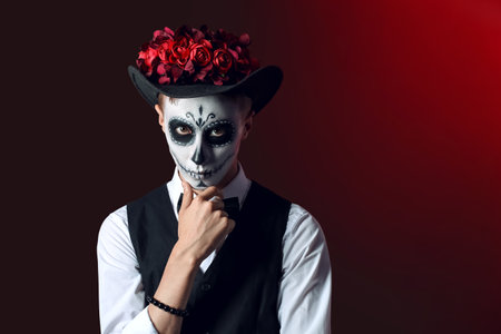 Young man with painted skull on his face for Mexico's Day of the Dead (El Dia de Muertos) against dark backgroundの写真素材