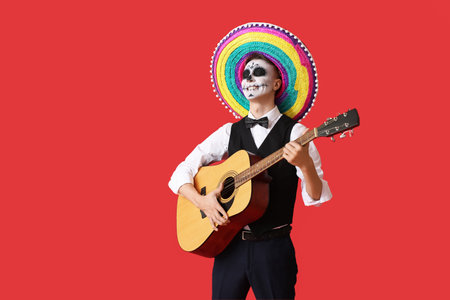 Young man with painted skull on his face and guitar against color background. Celebration of...