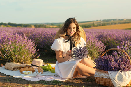 Beautiful young woman having picnic in lavender fieldの写真素材