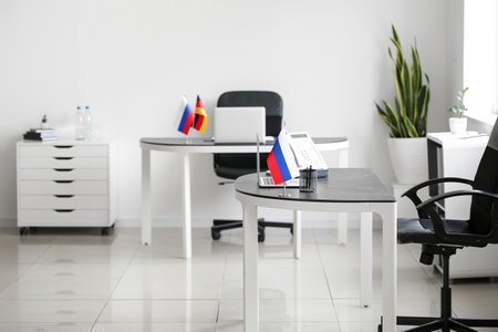 Russian flag, stationery holder, laptop and landline phone on table in officeの写真素材