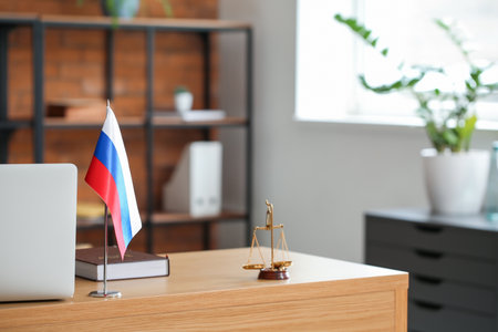 Russian flag, book, judge scales and laptop on table in officeの写真素材