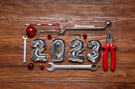 Figure 2023 made of balloons with worker's tools and Christmas balls on wooden backgroundの写真素材