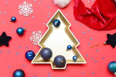 Plate in shape of Christmas tree with decor and Santa hat on red backgroundの写真素材