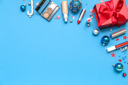 Frame made of makeup products with Christmas decor and gift on blue backgroundの写真素材