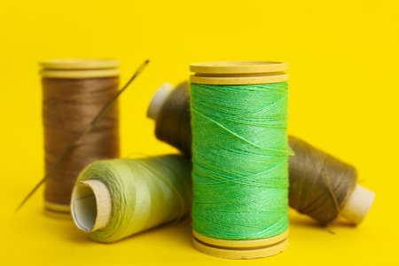 Thread spools with needles on yellow background, closeupの写真素材