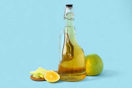Bottle of apple cider vinegar and fruits on color backgroundの写真素材