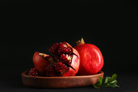 Plate with fresh pomegranates on dark backgroundの写真素材