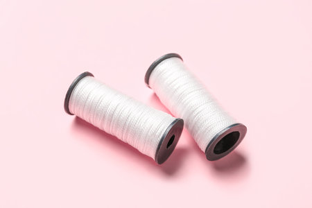 White thread spools on pink background