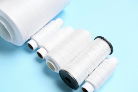 Set of different thread spools on color background, closeup