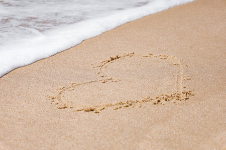 Drawn heart on sand near sea, closeup