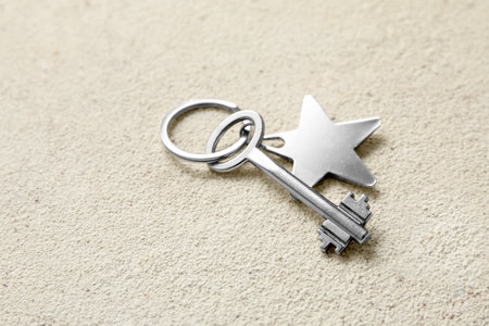 Key with star shaped keychain on light background