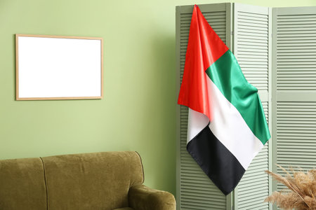 UAE flag hanging on folding screen near green wallの写真素材