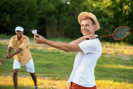 Young men playing badminton outdoorsの写真素材