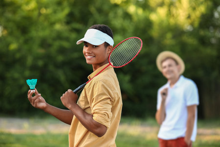 Young men playing badminton outdoorsの写真素材