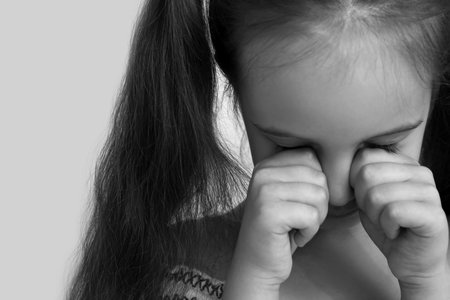 Crying little girl on light background, closeupの写真素材