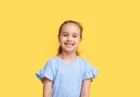 Portrait of smiling little girl on yellow background