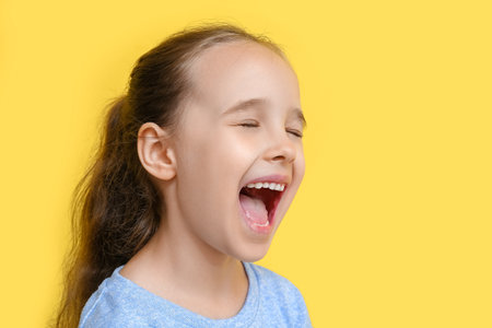 Portrait of shouting little girl on yellow background, closeupの写真素材