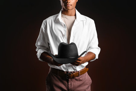 Handsome stylish African-American guy with hat on dark backgroundの写真素材